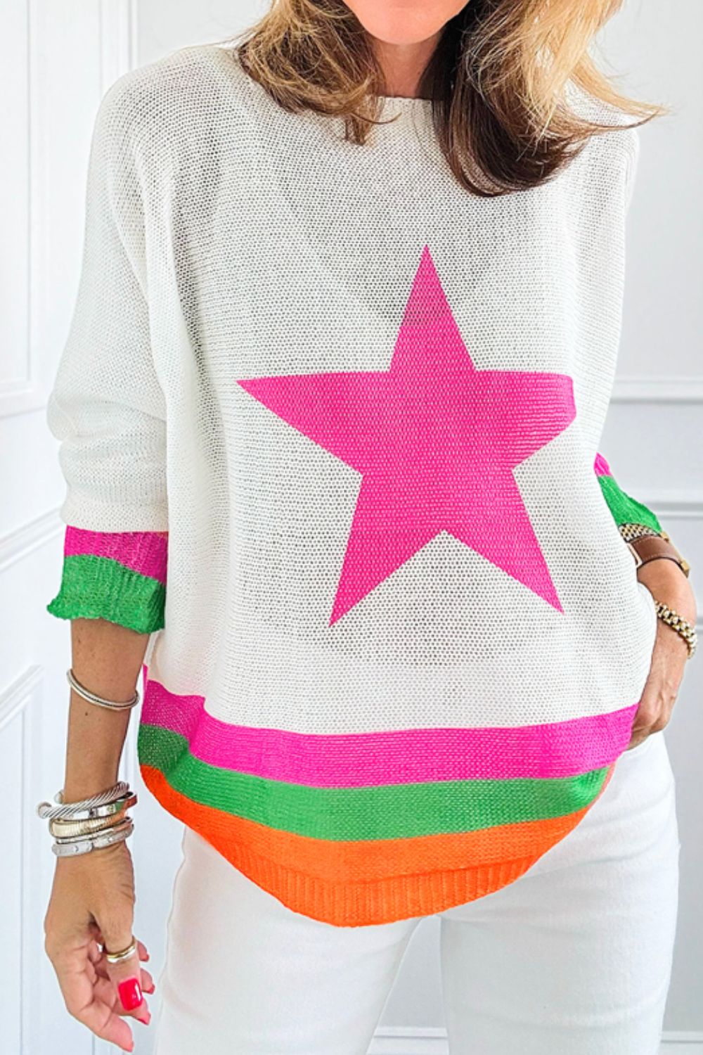 White knit sweater with a large pink star and striped hem.