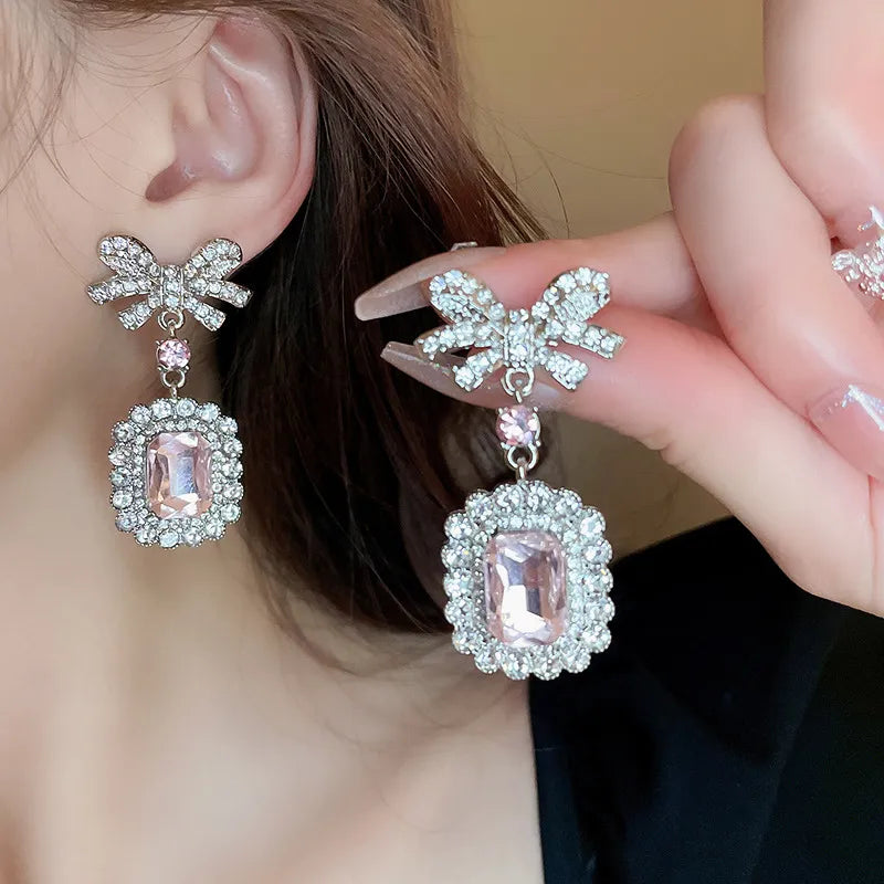 Silver bow crystal drop earrings with pink gemstone and crystal accents.