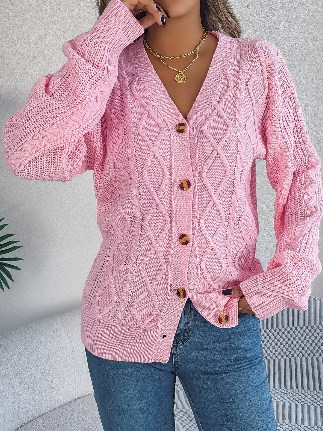 Blush pink cable knit balloon sleeve cardigan with button front and v-neck.