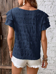 Dark blue smocked blouse with ruffle sleeves and textured fabric.
