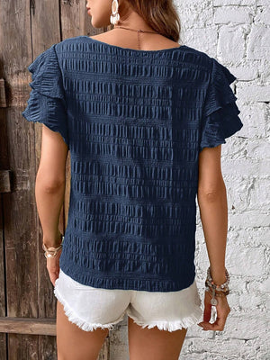Dark blue smocked blouse with ruffle sleeves and textured fabric.