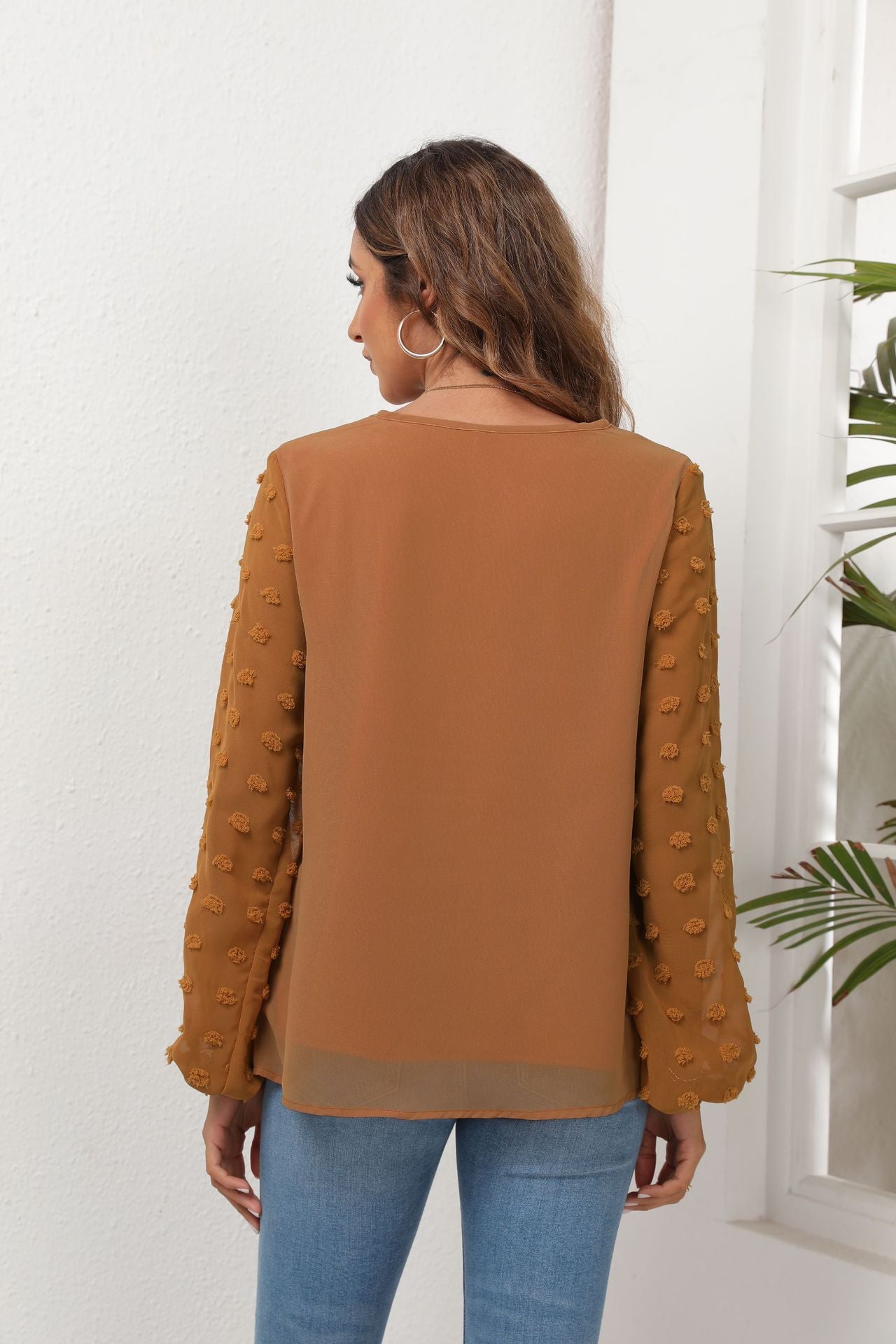Camel V-neck blouse with textured pom-pom balloon sleeves.