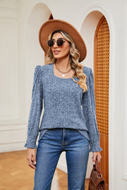 Textured blue knit blouse with square neckline and cuffed sleeves.
