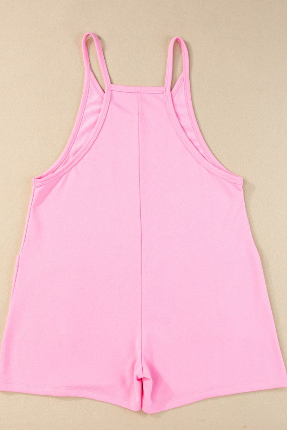 Pink spaghetti strap romper with patch pockets and a square neckline.