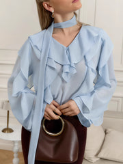 Light blue chiffon blouse with ruffle trim, V-neck, and tie detail.