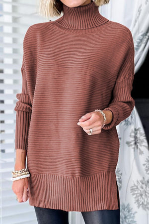 Oversized brick red ribbed turtleneck sweater with extended hem and ribbed cuffs.
