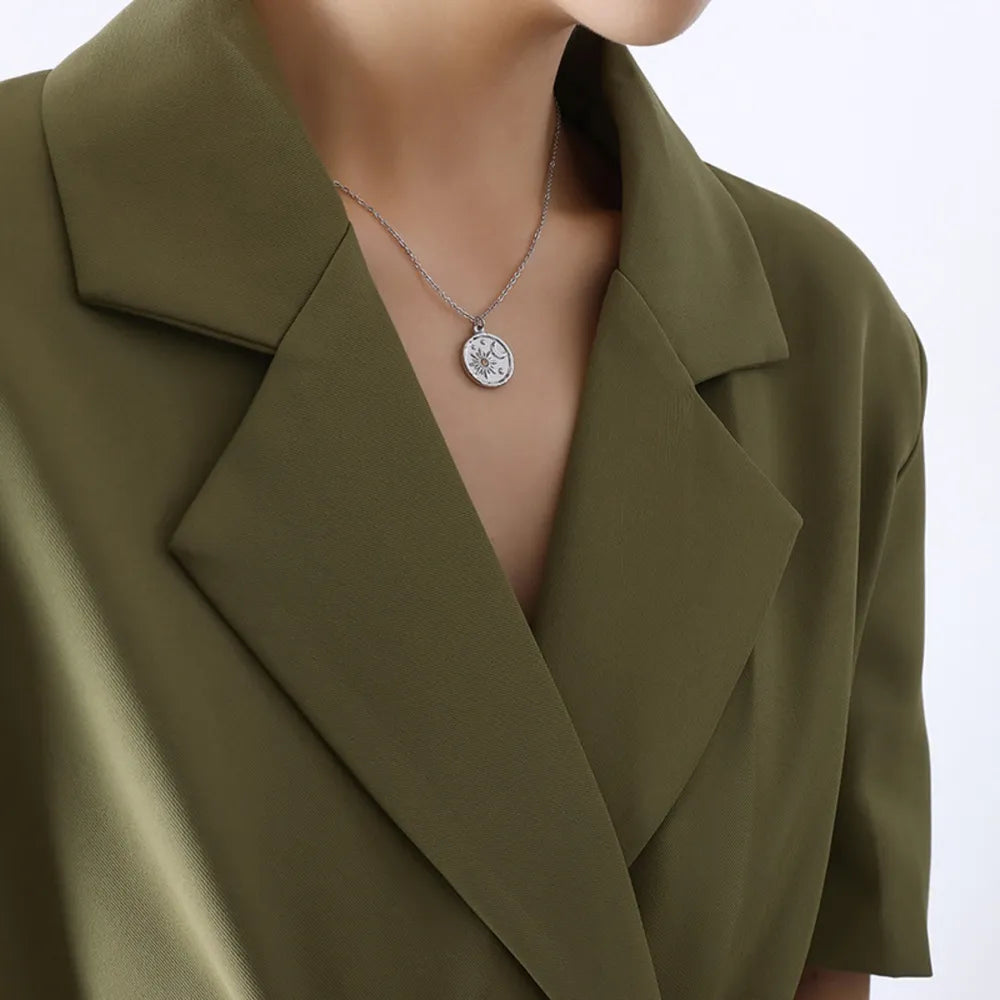 Silver coin necklace with sun and moon detail, styled with a green blazer.