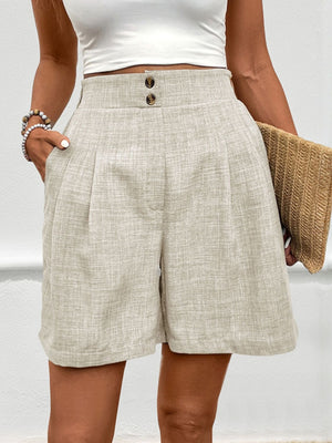 Beige linen shorts with high waist, pleats, and button closure.
