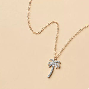 Gold palm tree pendant necklace with crystal accents on a delicate chain.