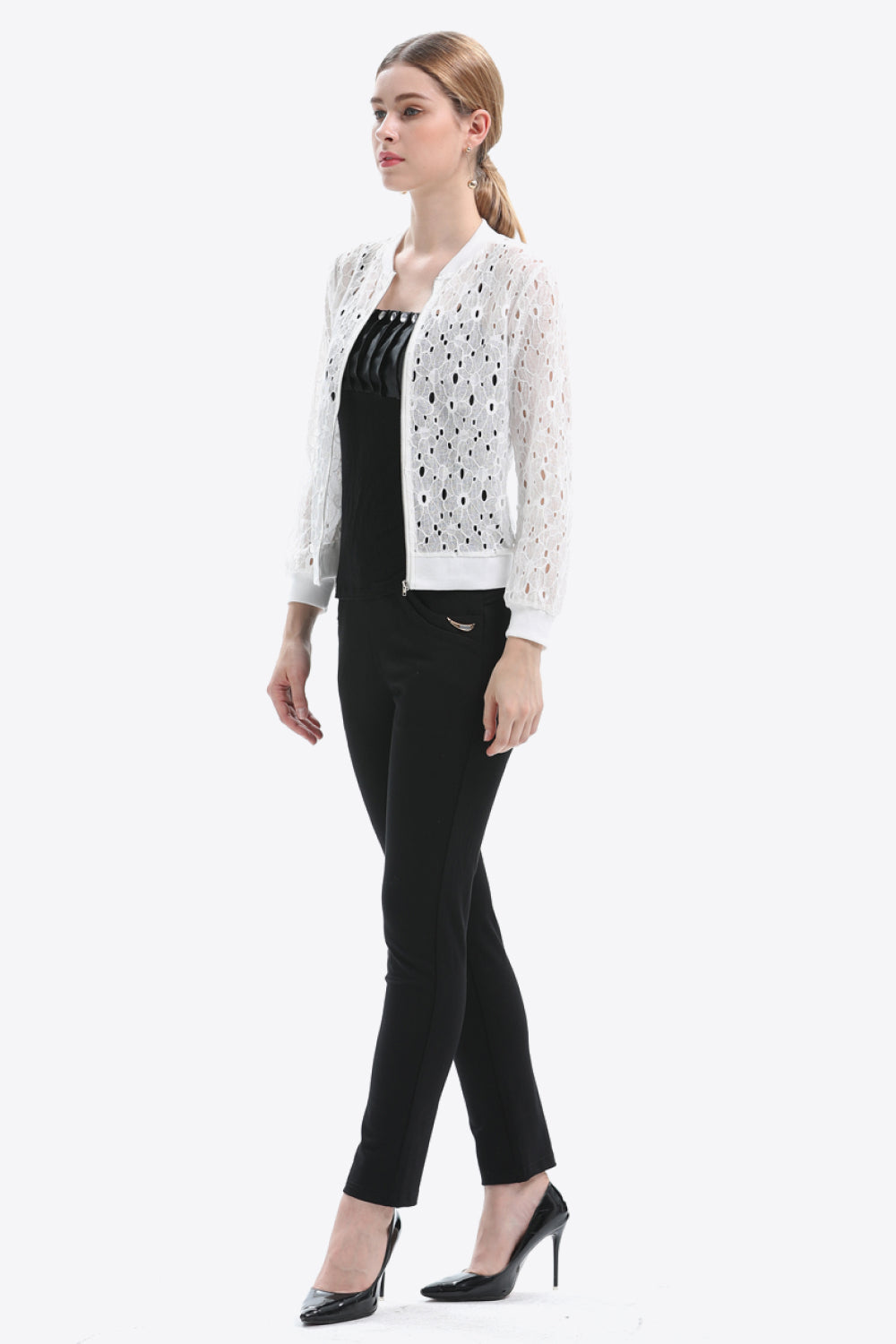 White lace-cut bomber jacket with a zip front and ribbed cuffs, styled with black pants.