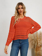 Orange-red openwork knit sweater with crewneck and long sleeves, featuring textured details.