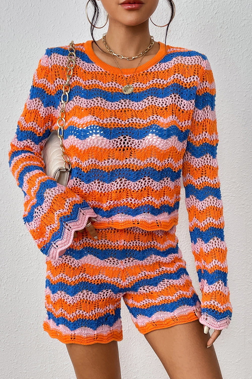 Crochet flare set with orange-red, blue, and pink wavy stripes, bell sleeves, and shorts.