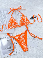 Leopard print tie-side bikini set in tangerine with white spots, featuring a halter top and cheeky bottoms.