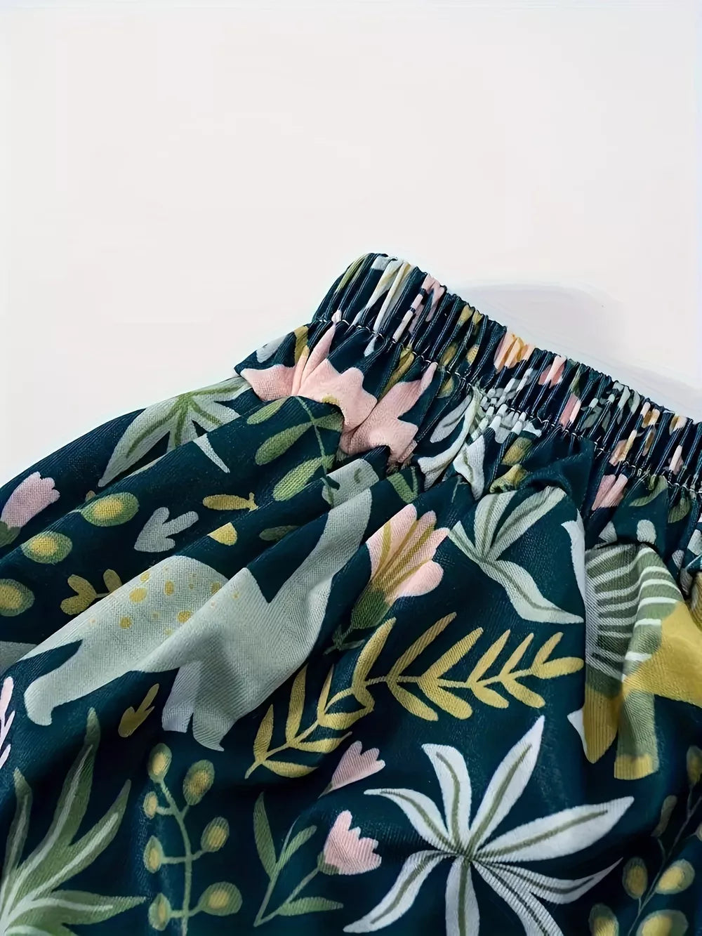 Dinosaur print elastic waist skirt in dark green with botanical accents and pink flowers.