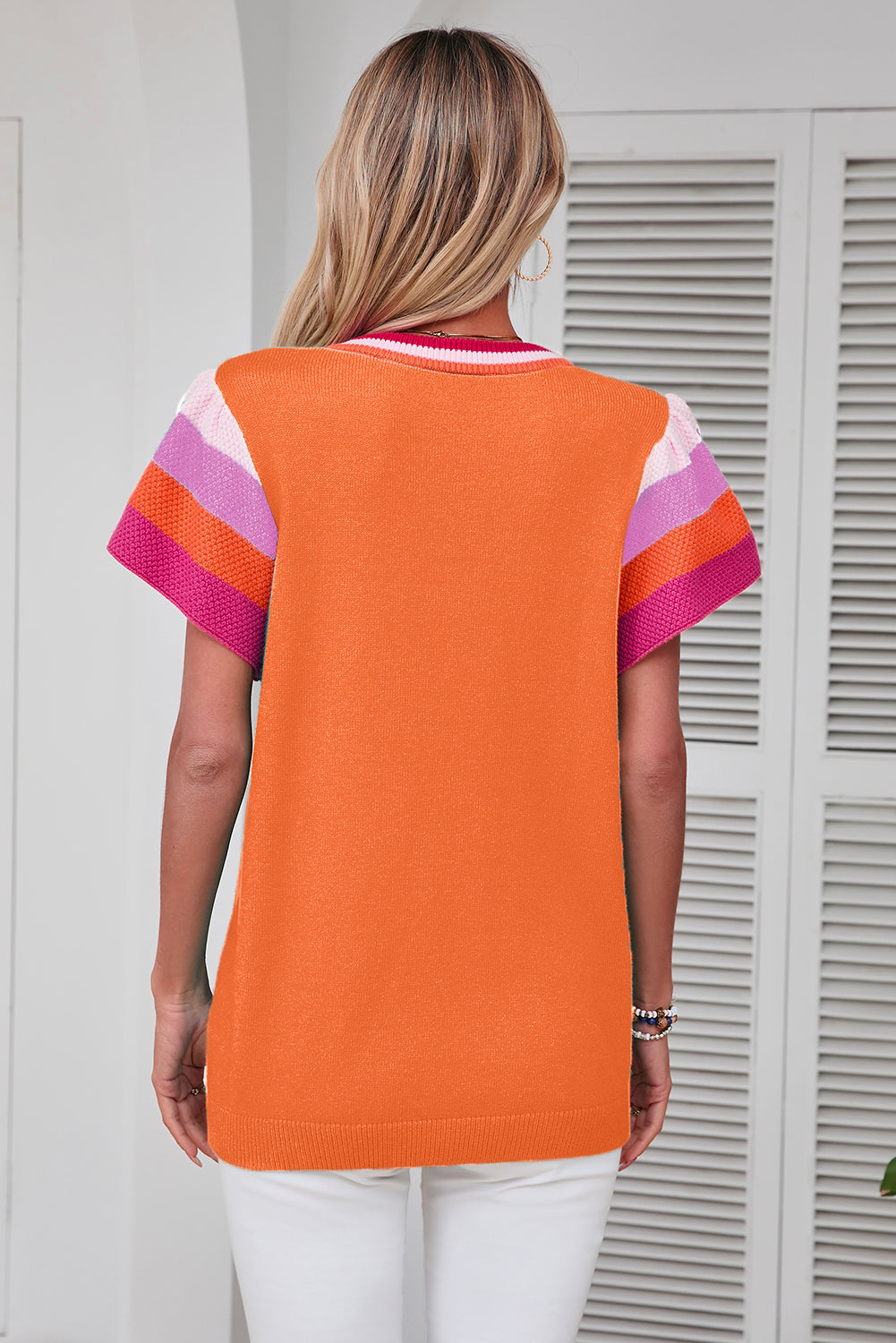 Orange knit blouse with colorblock flutter sleeves and striped neckline trim.