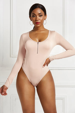 Long sleeve beige bodysuit with plunge neckline and zip front detail.