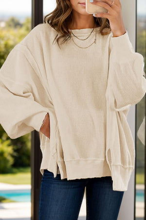 Ivory waffle knit pullover sweater with slit sleeves and a relaxed fit.
