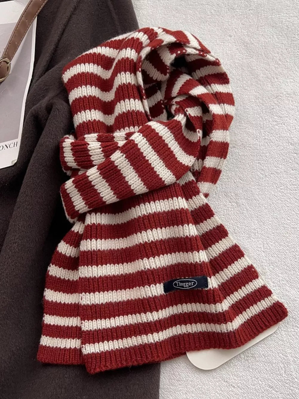 Cozy wool striped winter scarf in deep red and cream with a small navy tag.