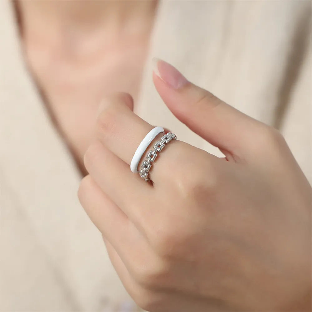 Chain link and white enamel open rings stacked on a finger