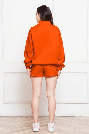 Orange quarter-zip loungewear set with shorts and a mock neck sweatshirt.