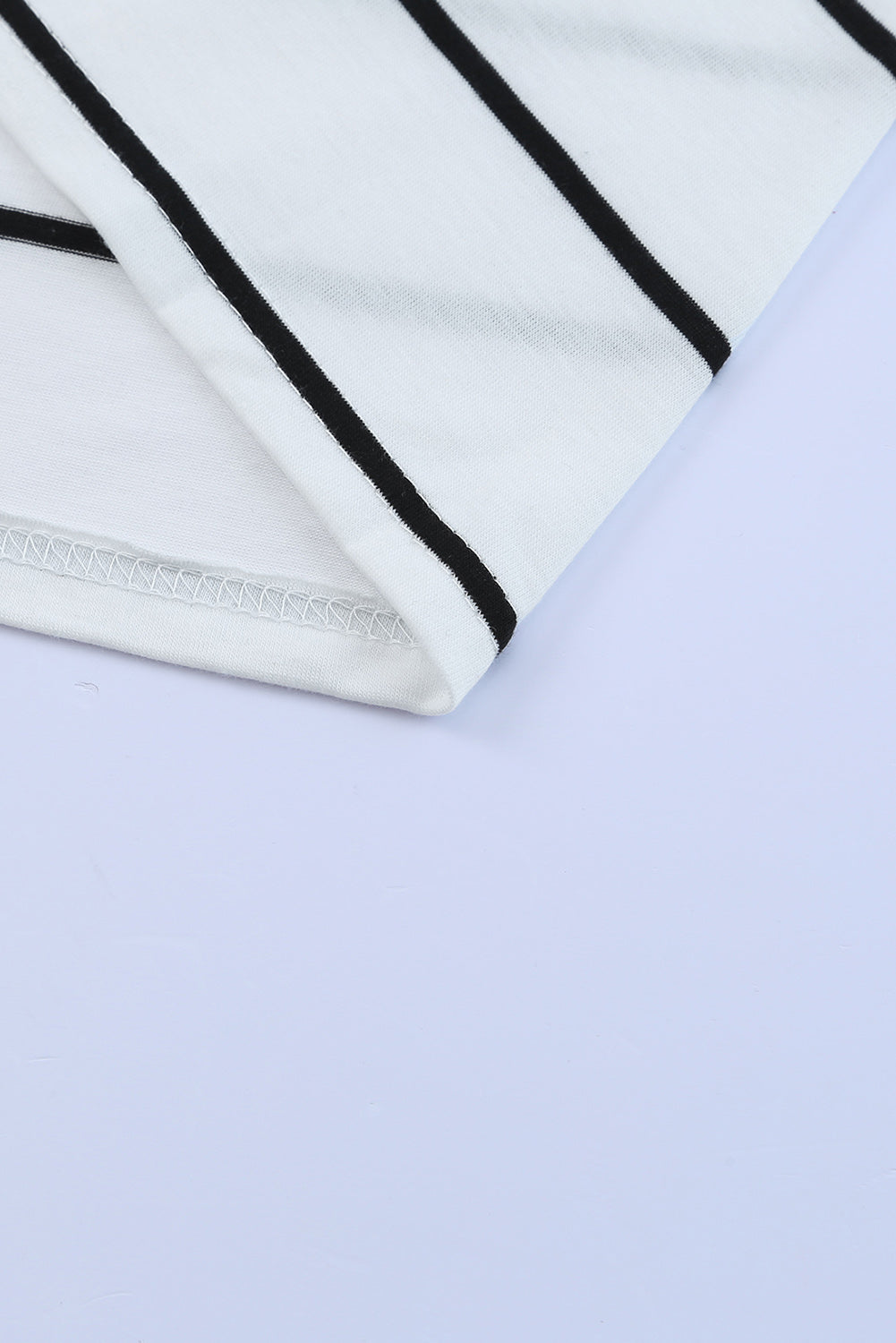 White maxi dress with black horizontal stripes and a slit hem detail.