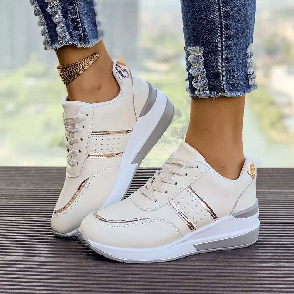 White lace-up sneakers with metallic rose gold accents and a chunky sole.