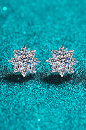 Silver blossom earrings with moissanite stones on a teal glitter background.