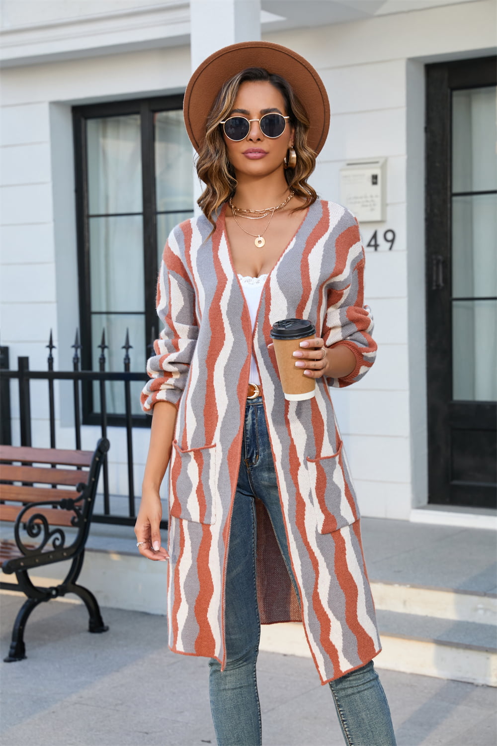 Longline knit cardigan with wave stripe pattern in rust, grey, and white, featuring pockets.