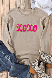 Tan ribbed sweatshirt with pink XOXO appliqué and gold trim