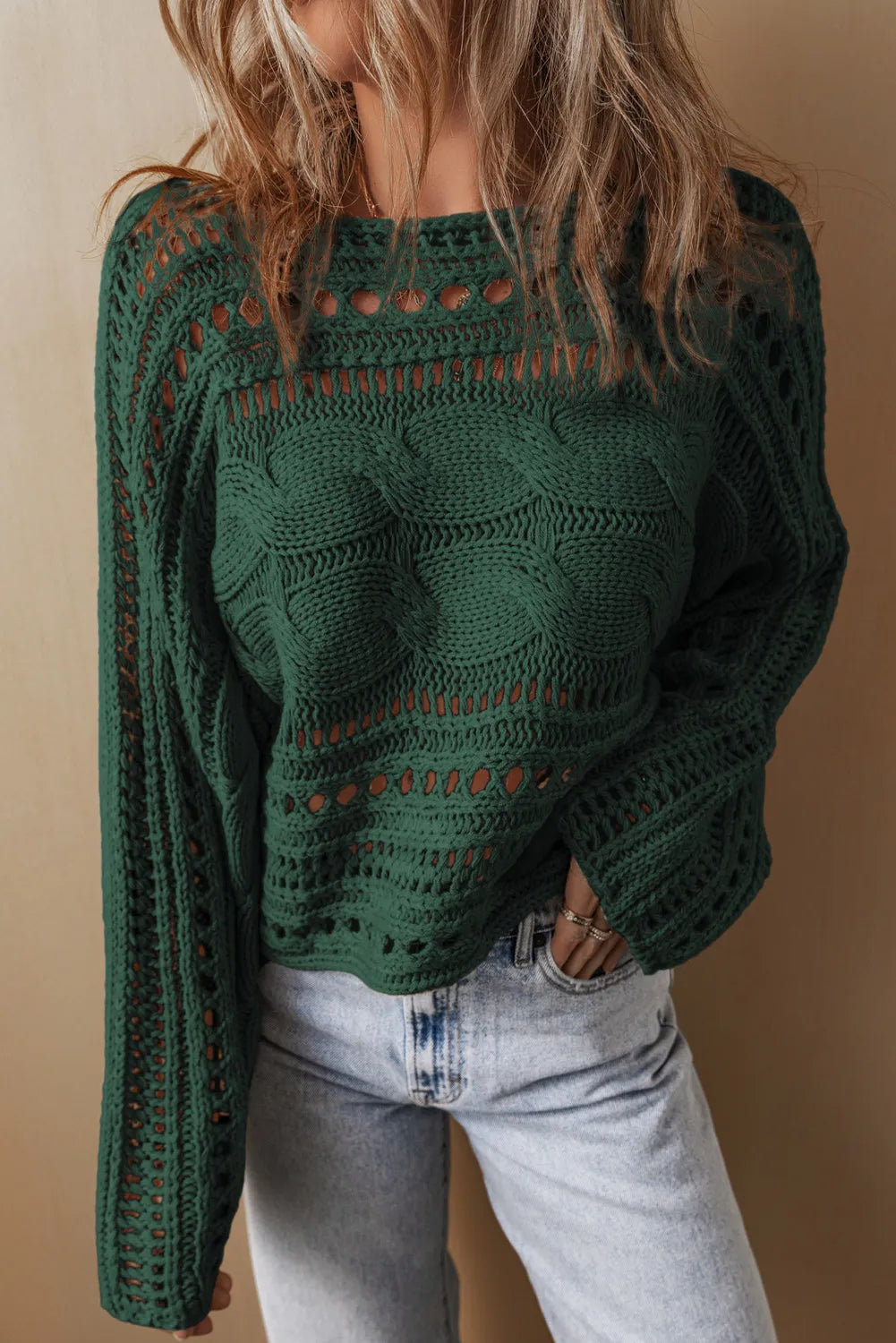 Dark green cable knit sweater with cutout details and a crew neck.