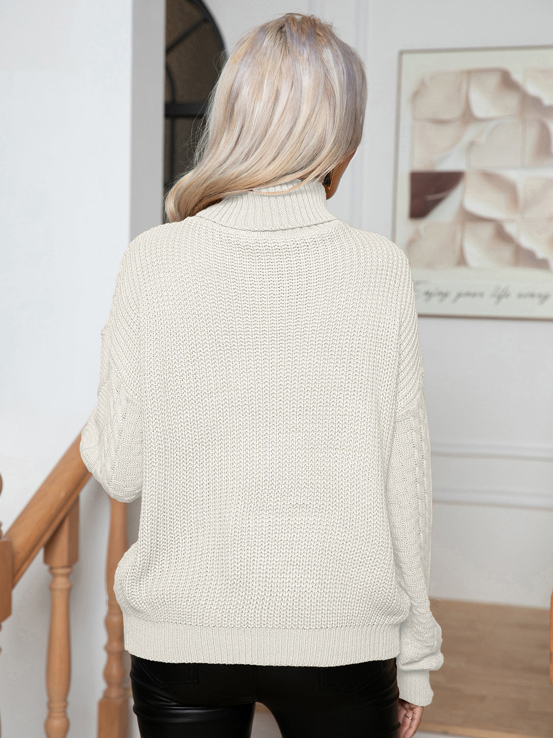 White acrylic cable knit turtleneck sweater with textured details.