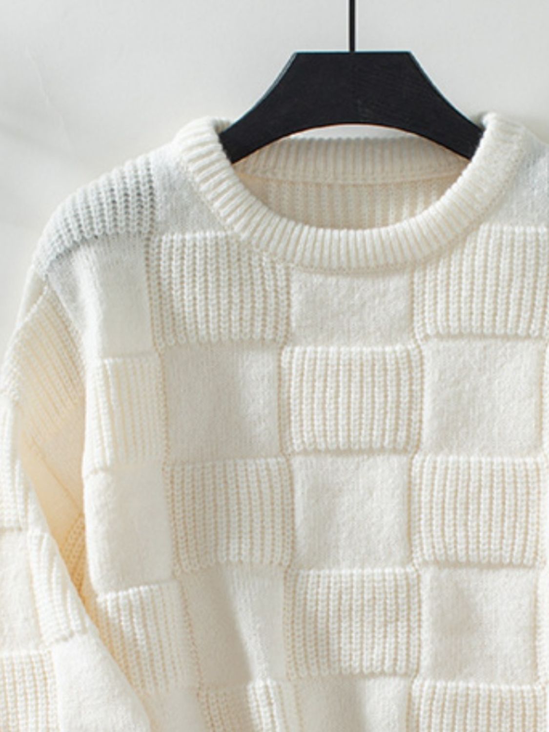 Cream checkerboard knit pullover sweater with textured squares and crew neck.