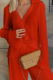 Orange-red pleated shirt and wide-leg trousers set with button detail and flared sleeves.