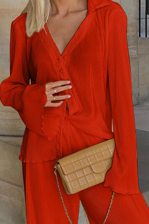 Orange-red pleated shirt and wide-leg trousers set with button detail and flared sleeves.