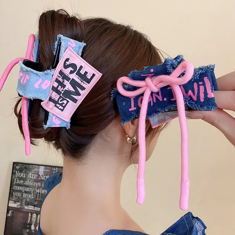 Denim patchwork claw clip with pink drawcord and text detail.