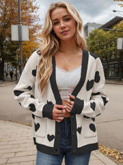 Cream acrylic cardigan with black heart intarsia pattern, button front and pockets.