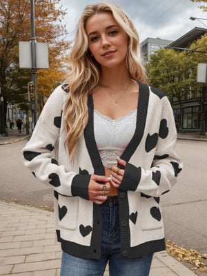 Cream acrylic cardigan with black heart intarsia pattern, button front and pockets.