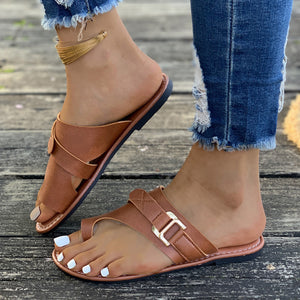 Brown toe loop flat sandals with buckle detail and crisscross straps.
