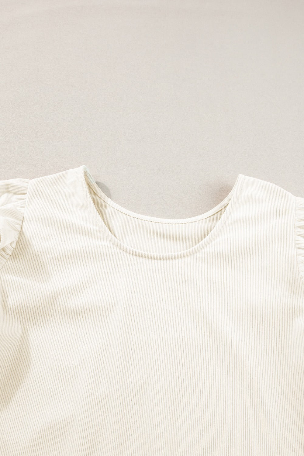 Eggshell textured blouse with ruffle sleeves and a scoop neckline.