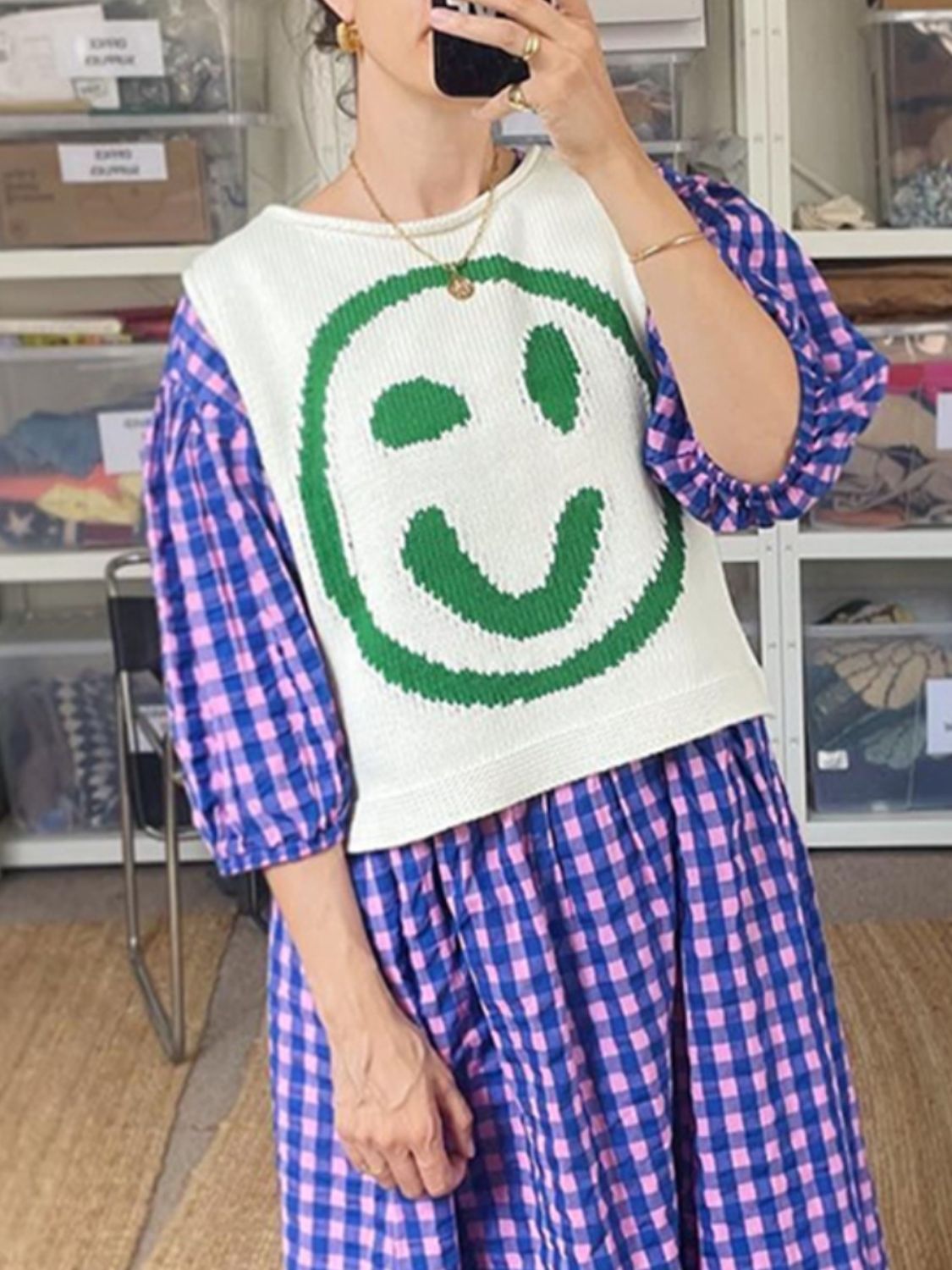 White knit tank top with green smiley face graphic, paired with a blue and pink gingham dress.