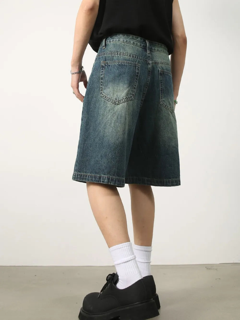 Baggy denim bermuda shorts in washed light blue with buttoned closure and distressed details.