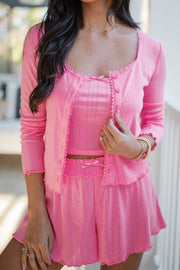Pink knit lounge set with lace trim, featuring a button-up cardigan and matching shorts with bows.