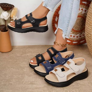 Platform sandals in black, blue, and ivory with adjustable straps and white stitching detail.