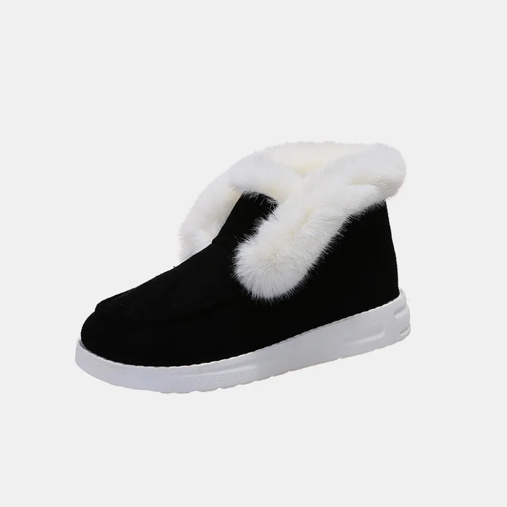 Black suede slip-on booties with white shearling trim and white sole.