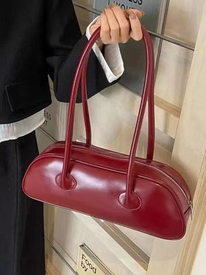 Chic red leather barrel shoulder bag with a zip closure and sleek top handles.