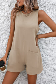 Tan romper with round neck, sleeveless, and two front pockets.