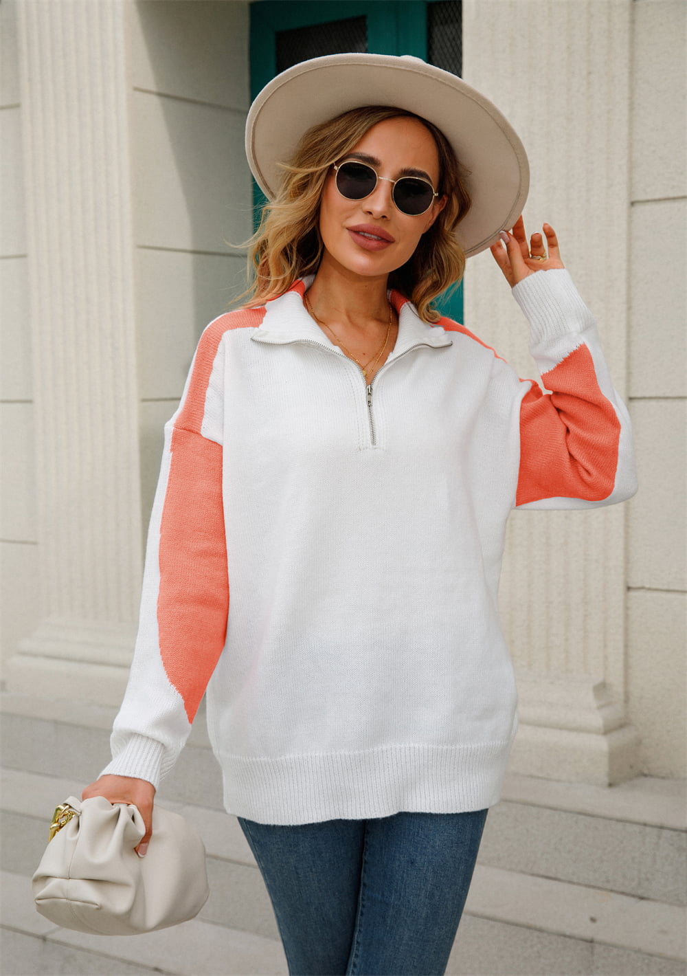 Colorblock zip-neck knit pullover in white with orange sleeves and side panels.