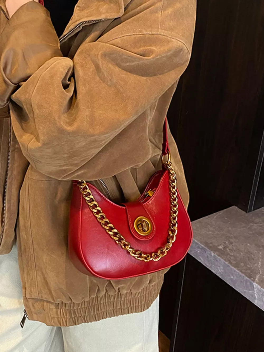 Crescent mini shoulder bag in wine red with gold chain accent and turn-lock closure.