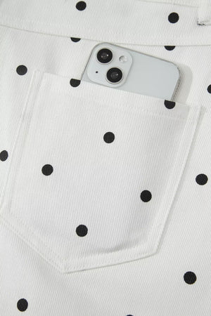 White chino shorts with black polka dots and a back pocket holding a smartphone.