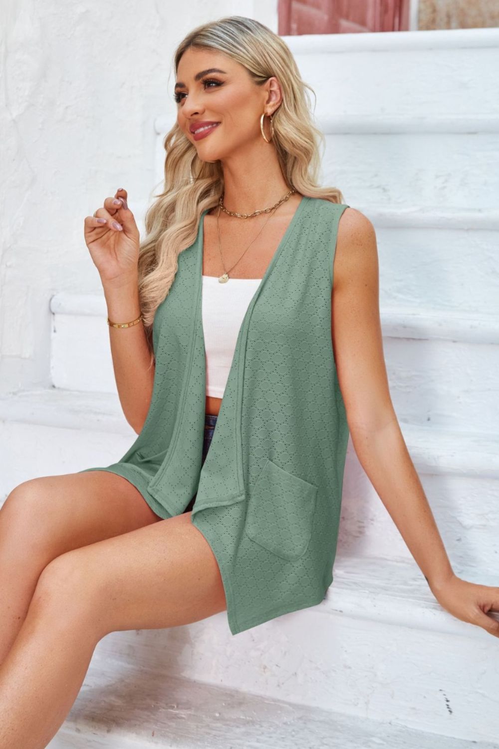 Sage eyelet drape front vest with pockets and open neckline.